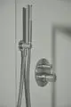Brausearmatur von Ideal Standard mit eksternem Thermostat und zwei Reglern, montiert an einer hellen Wand. Edelstahloptik, flexible Brauseschläuche.